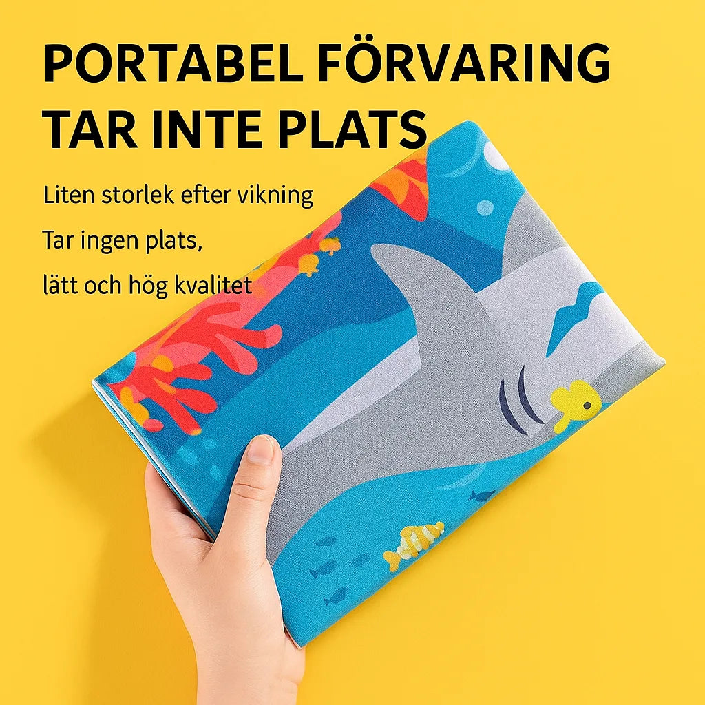 Hand håller hopvikt vattenmatta med hajmotiv mot gul bakgrund – text på svenska visar att produkten är lätt, kompakt och enkel att förvara.